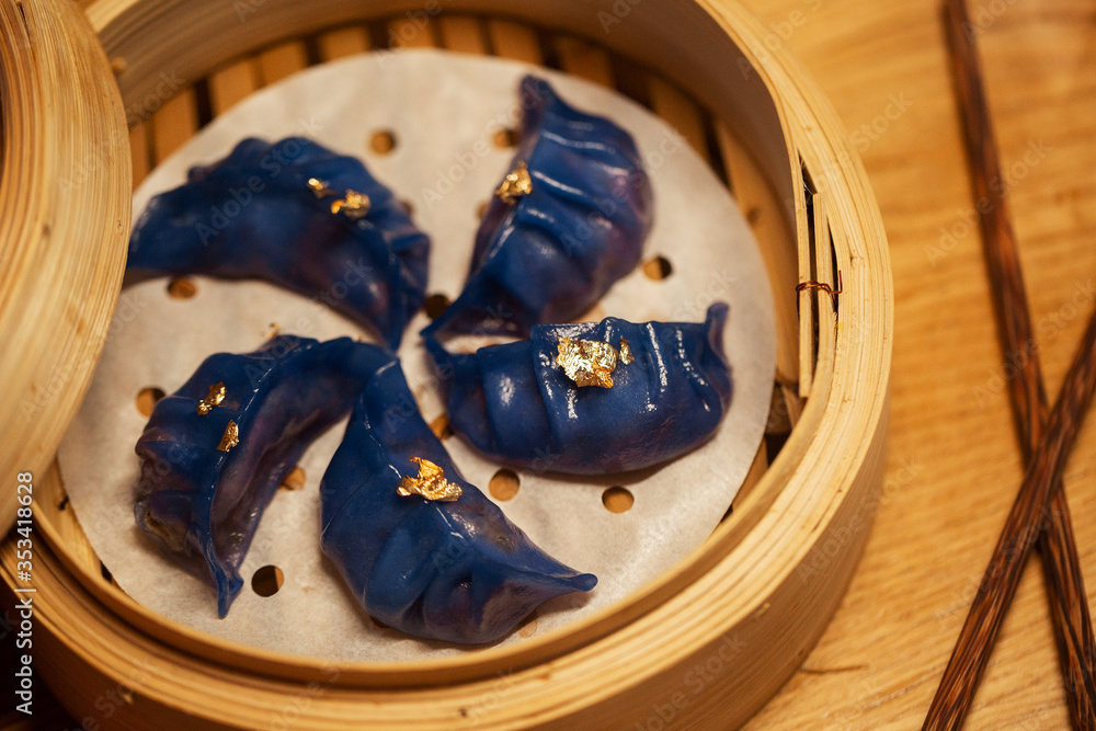Blue Dim Sum chinese cuisine in bamboo steamer and pot. Top view fresh dumplings with hot steams on wood plate with chopsticks. High angled view of cooked dumplings .
