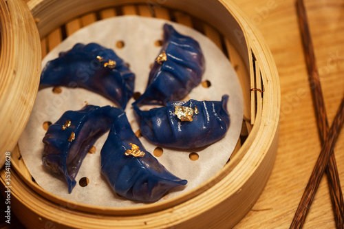 Obraz na płótnie Blue Dim Sum chinese cuisine in bamboo steamer and pot. Top view fresh dumplings with hot steams on wood plate with chopsticks. High angled view of cooked dumplings . w salonie