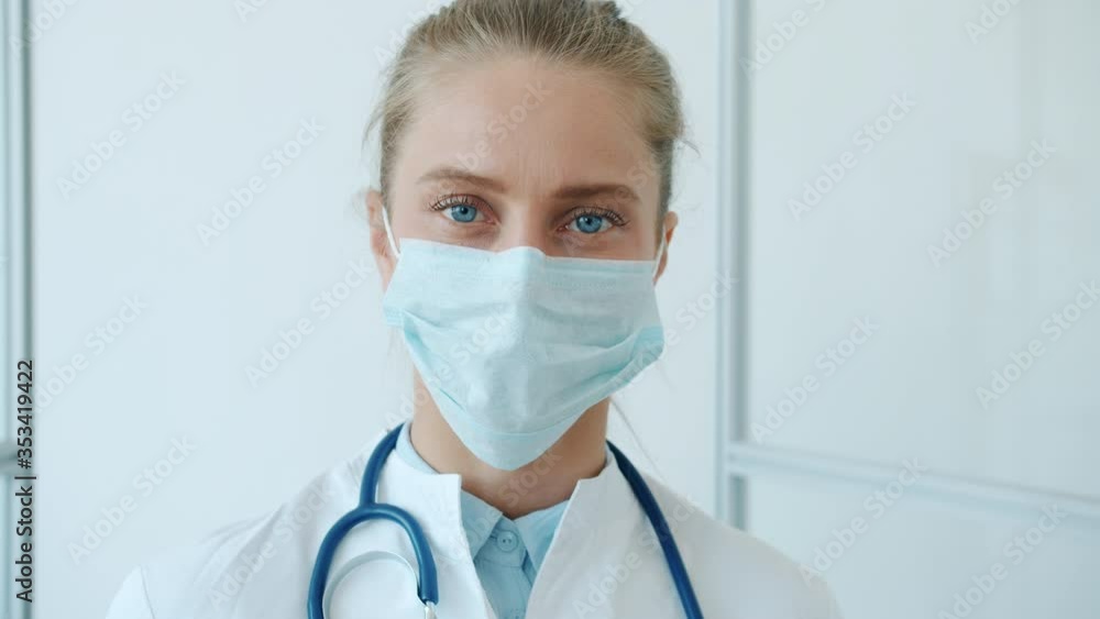 Portrait of young blond woman doctor wearing medical protective mask in clinic during pandemic of corona virus. People, occupation and healthcare concept. Portrait of young blond woman doctor wearing medical protective mask in clinic during pandemic of corona virus. People, occupation and healthcare concept.