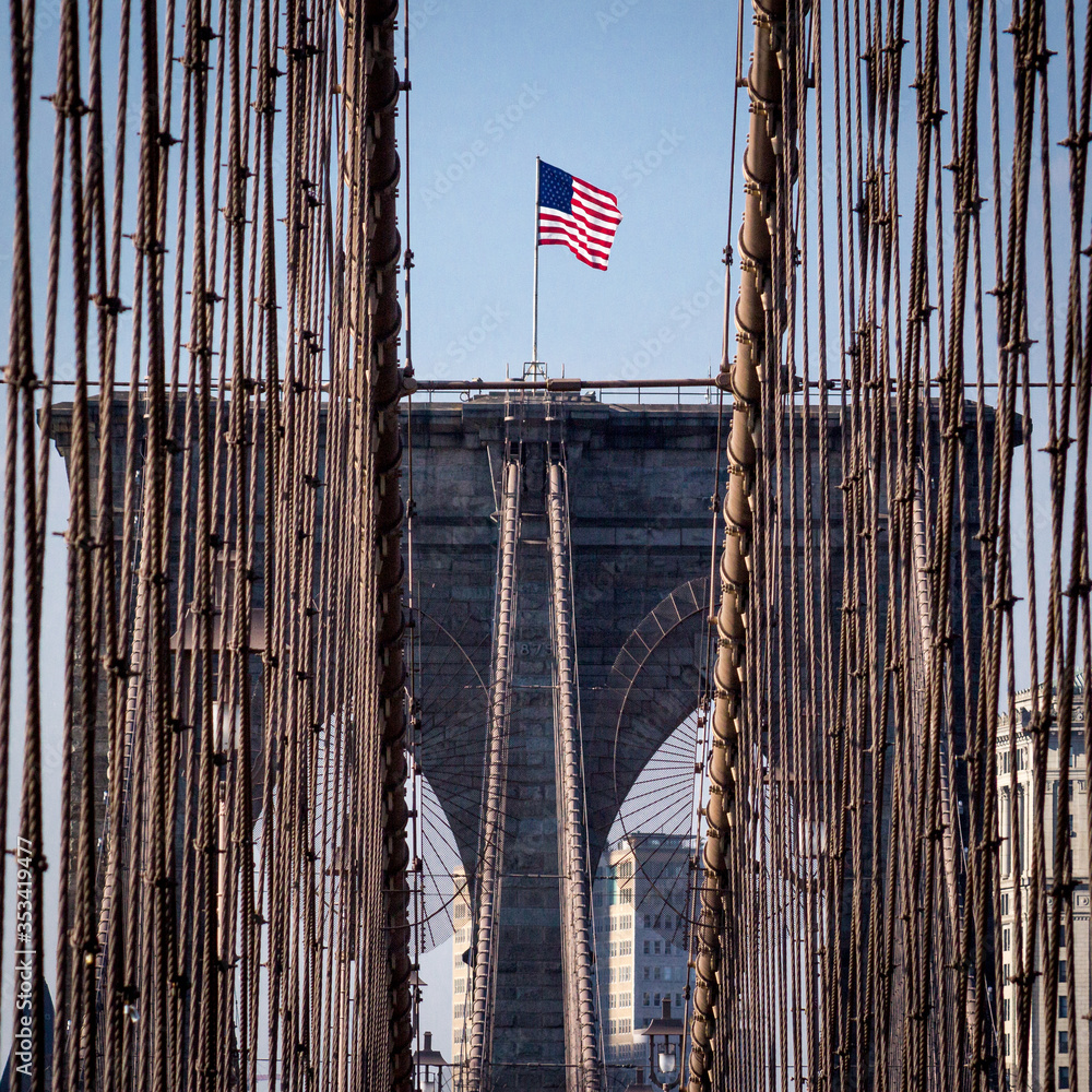 Obraz premium New York City, USA - October 18, 2016: American flag on top of Brooklyn Bridge