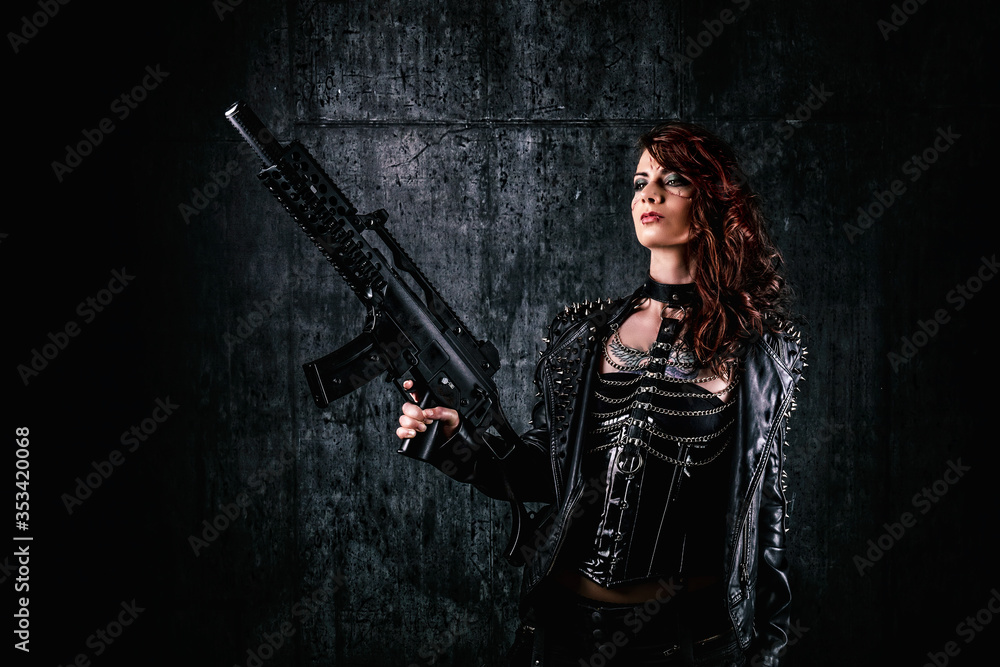 Young woman with scarified face, wearing a studded leather jacket, holding an assault rifle in her hands