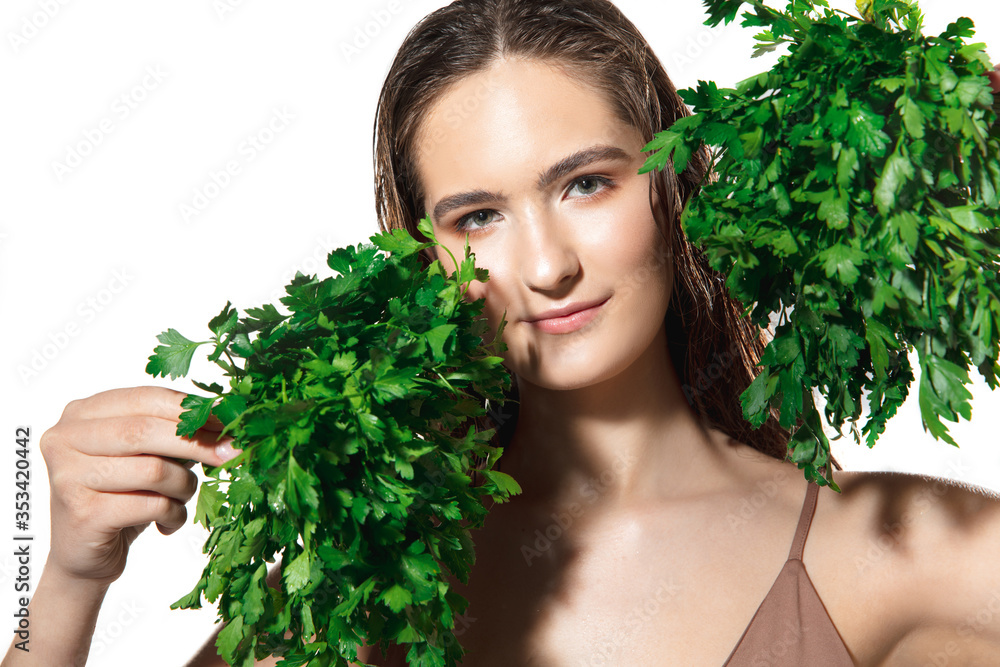 Green splash. Close up of beautiful young woman with parsley on white background. Concept of cosmetics, makeup, natural and eco treatment, skin care. Shiny and healthy skin, fashion, healthcare. Green splash. Close up of beautiful young woman with parsley on white background. Concept of cosmetics, makeup, natural and eco treatment, skin care. Shiny and healthy skin, fashion, healthcare.