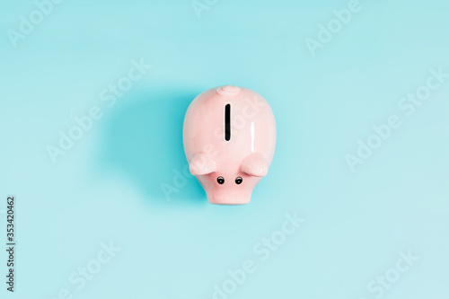 Pink piggy bank on pastel blue background. Flat lay, top view, copy space