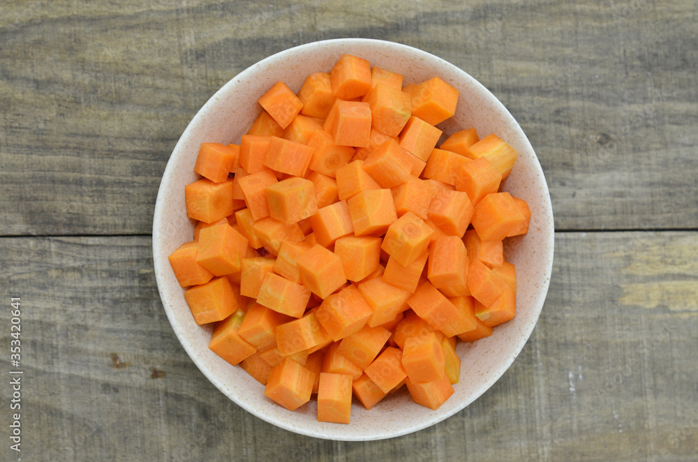 cuts cubes of carrot in bowl on wooden background cuts cubes of carrot in bowl on wooden background