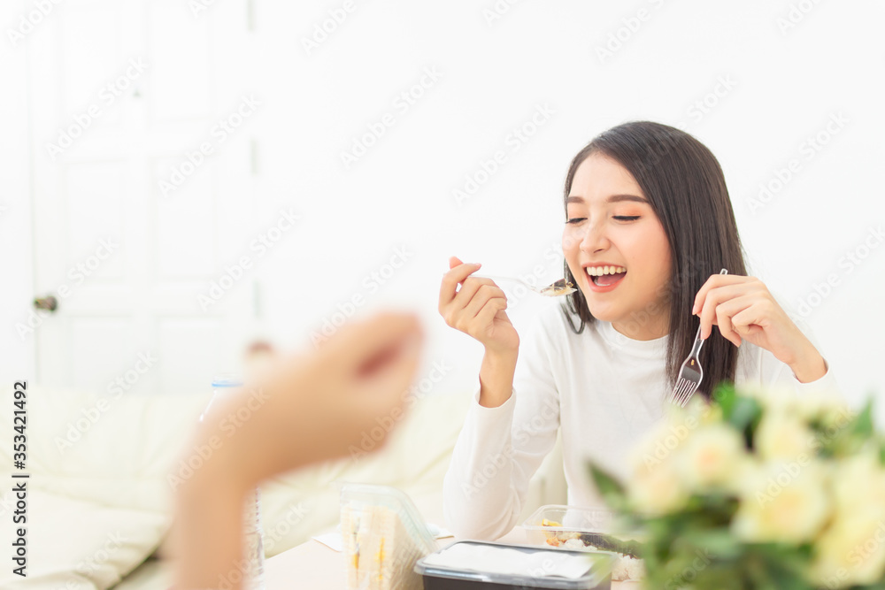 Two beautiful Asian women are sitting and eating new normal lifestyle couple friend use plastic spoon and fork eat food Two beautiful Asian women are sitting and eating new normal lifestyle couple friend use plastic spoon and fork eat food