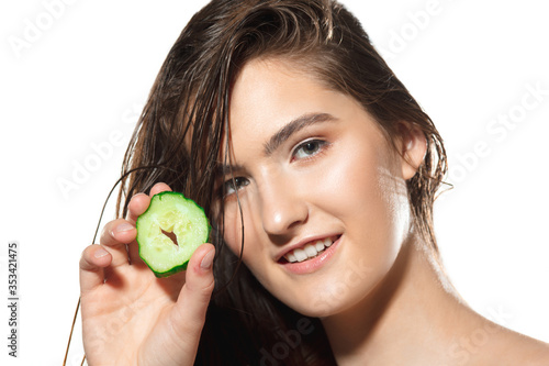 Fresh. Close up of beautiful young woman with cucumber slices on white background. Concept of cosmetics, makeup, natural and eco treatment, skin care. Shiny and healthy skin, fashion, healthcare.