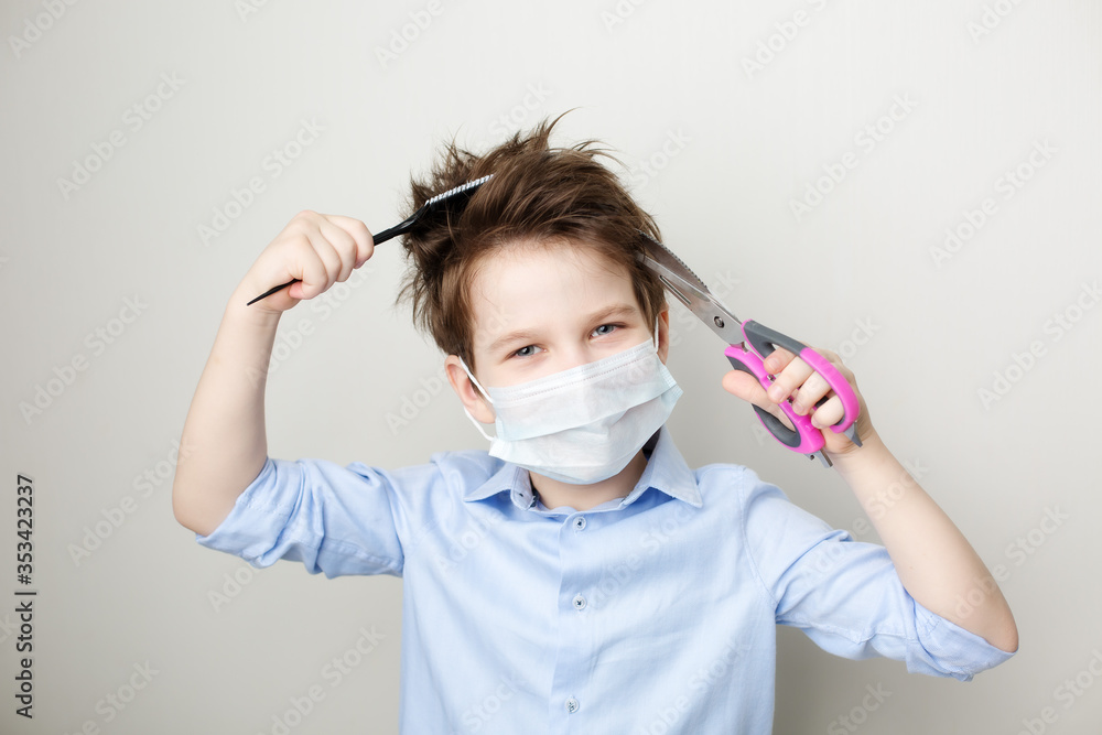 laughing boy in a medical mask holds a pair of scissors and a comb in his hands laughing boy in a medical mask holds a pair of scissors and a comb in his hands