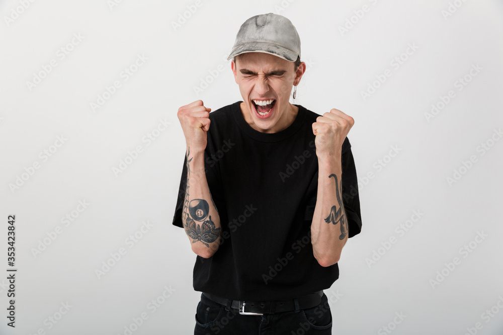Portrait of delighted excited man wearing black clothes screaming and clenching fists