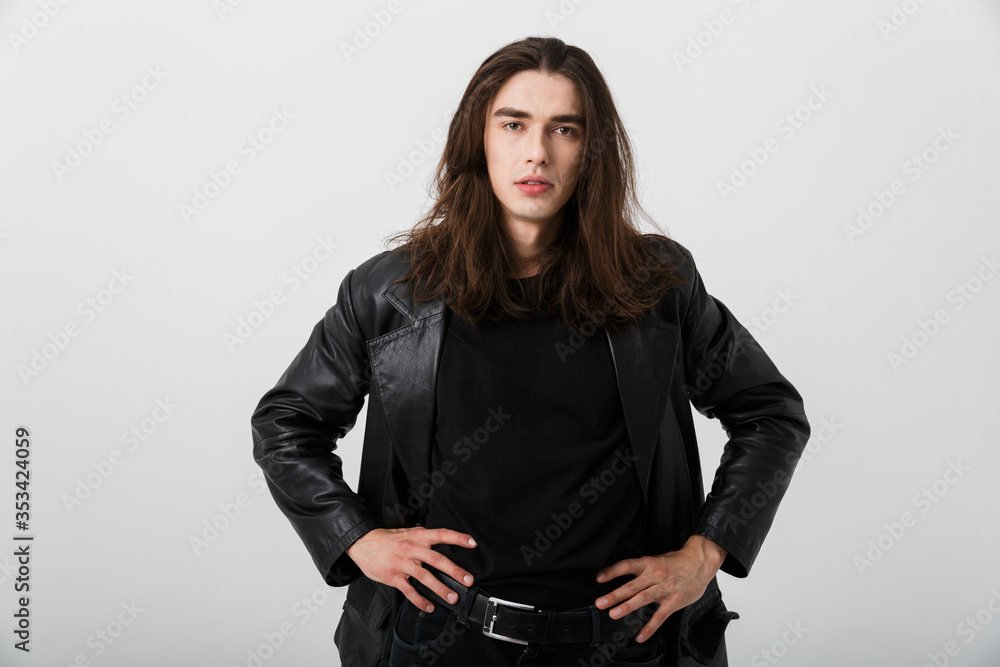 Portrait of brunette caucasian man with long hair wearing black lather jacket posing and looking at camera Portrait of brunette caucasian man with long hair wearing black lather jacket posing and looking at camera