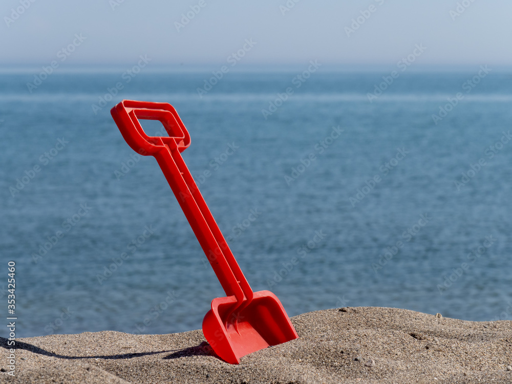 child's toy sand shovels on the hot beach at the seashore child's toy sand shovels on the hot beach at the seashore