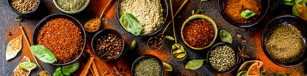 Set of Spices and herbs for cooking. Small bowls with colorful  seasonings and spices - basil, pepper, saffron, salt, paprika, turmeric. On black stone table top view copy space - obrazy, fototapety, plakaty 