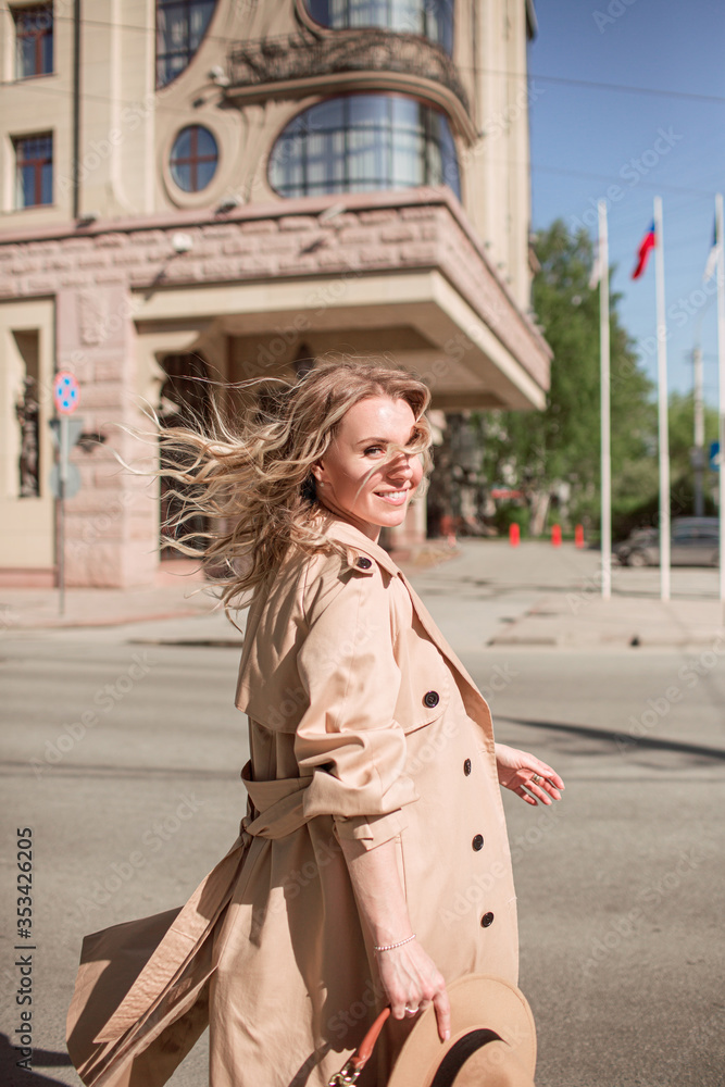 Fototapeta premium Young woman walking down the city street. Back view. Daytime stroll.