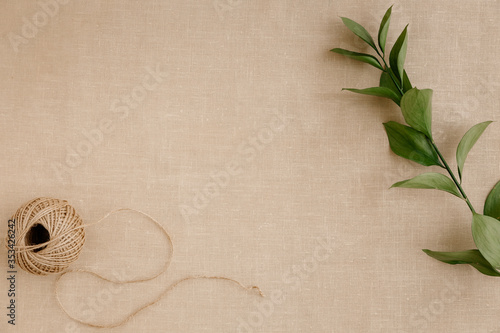 Top view image fashion designer background concept. Flat lay sewing scrapbooking accessory, skein of twine on modern brown linen fabric at home office desk studio.Space for creative design mock up.