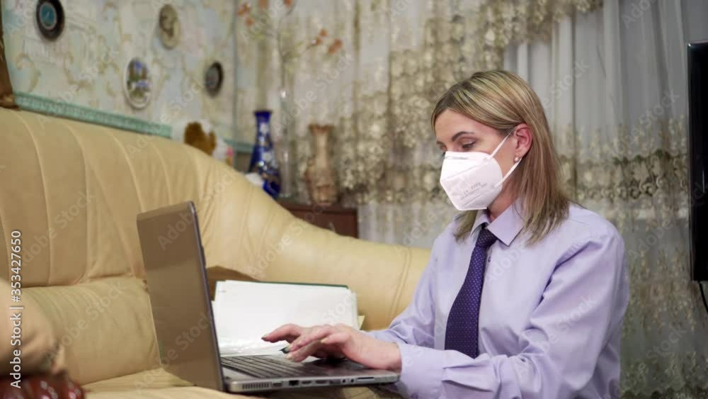 Portrait of a young woman in a protective mask and business clothes working at home away from the office. Self-isolation during quarantine.