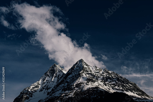 Peak of the mountains in the clouds on a background of blue sky.