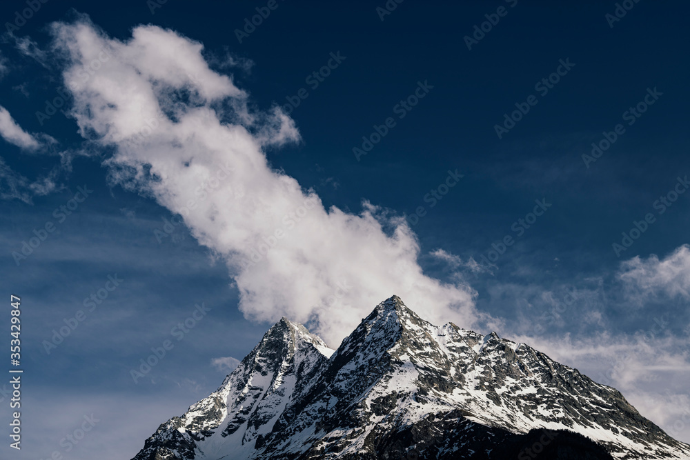 Peak of the mountains in the clouds on a background of blue sky.