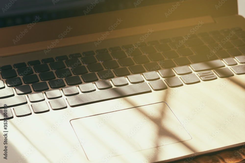 Obraz premium Close-up of a laptop keyboard in the morning sun. The concept of working in the morning. Hard shadows, light