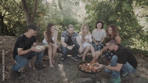 happy friends on a picnic cooked paella at the stake. Field kitchen in the forest