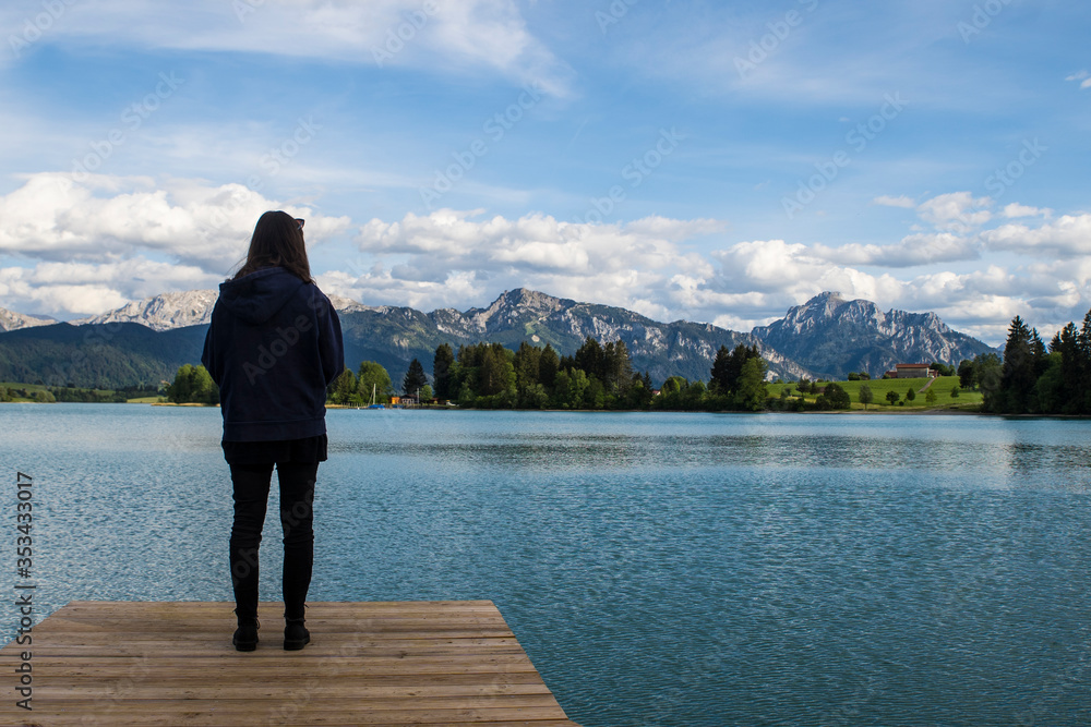 Frau au einem Steg vor einem schönem Panorama von Bergen und einem See