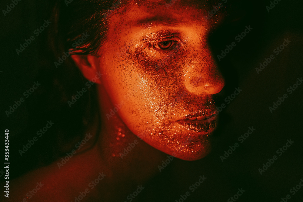 Female portrait with glitter face make up in dark with red light Female portrait with glitter face make up in dark with red light