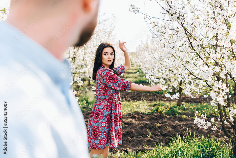 Loving couple hugging and walking. Lovestory in a blooming apple garden Loving couple hugging and walking. Lovestory in a blooming apple garden