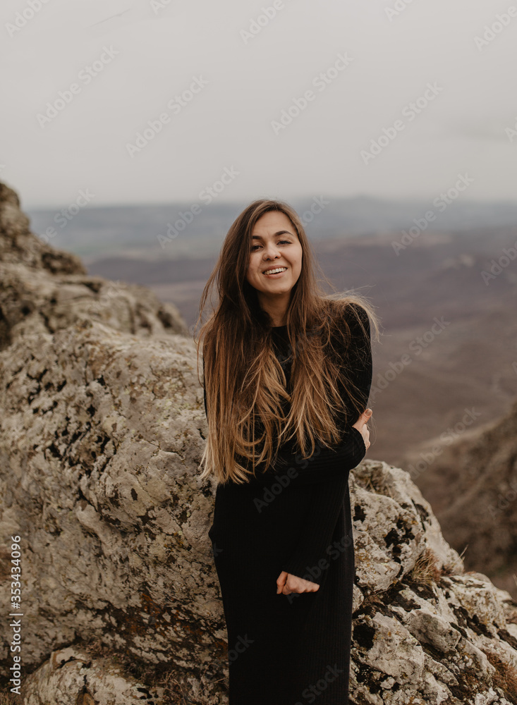 Young woman standing on the top of the hill.