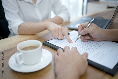 Saleswomen officers pointing to contract agreement document for the customer to fill out the documents correctly.