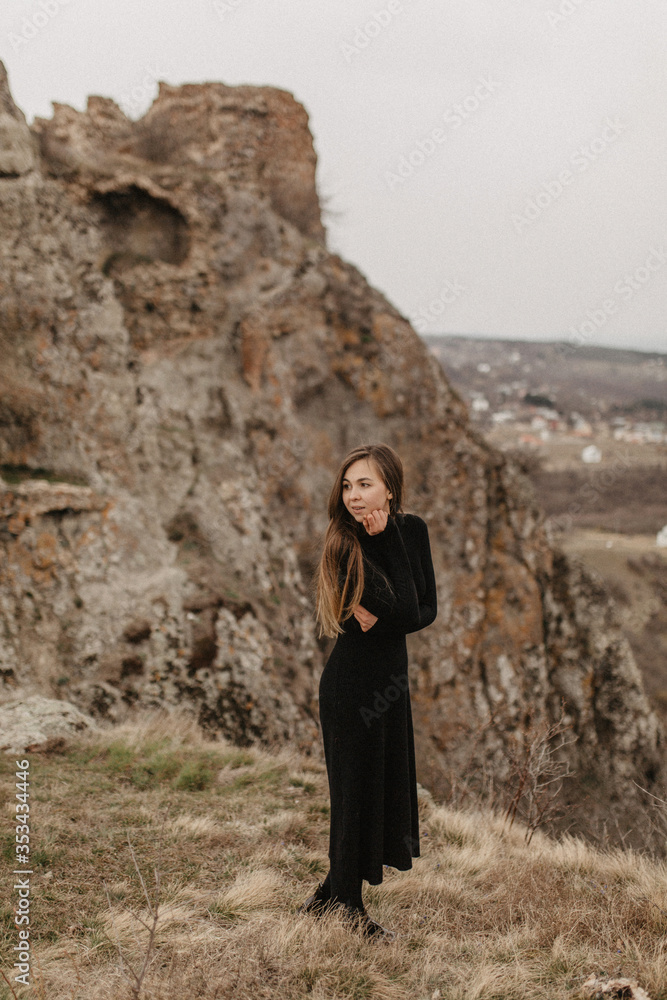 young woman in a black dress standing in the rocks