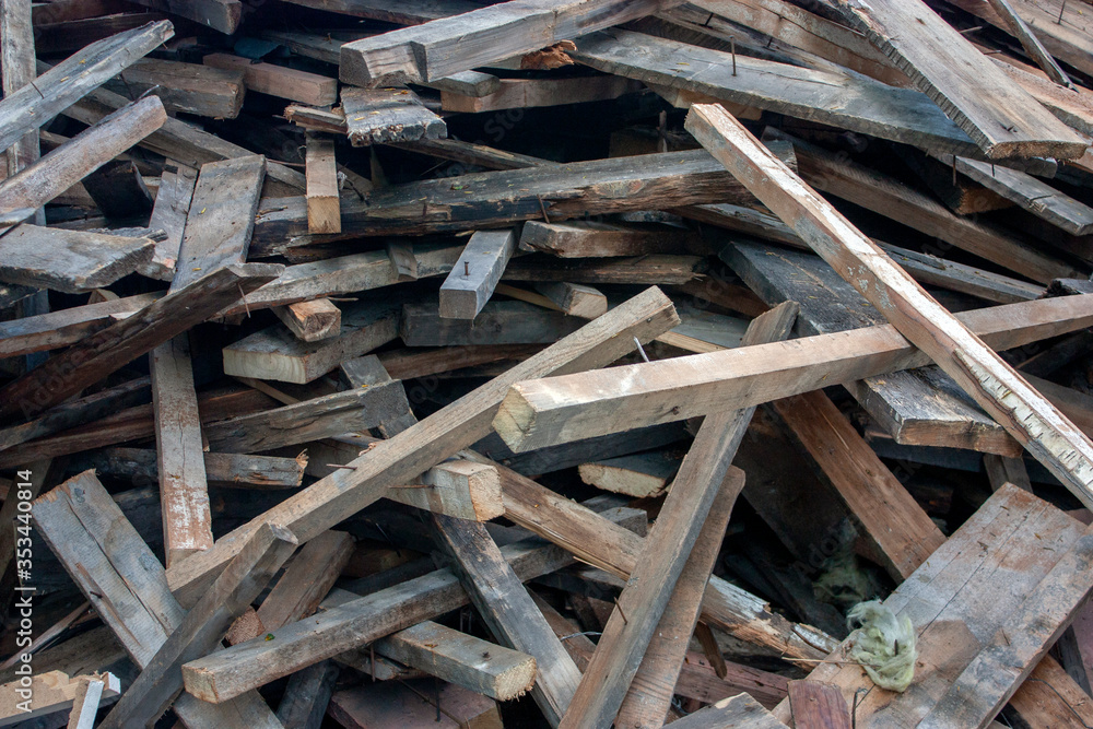 Wooden boards thrown into a chaotic pile. A pile of building material after the breaking of a wooden house. Wooden construction debris lies in a heap. Wooden boards thrown into a chaotic pile. A pile of building material after the breaking of a wooden house. Wooden construction debris lies in a heap.