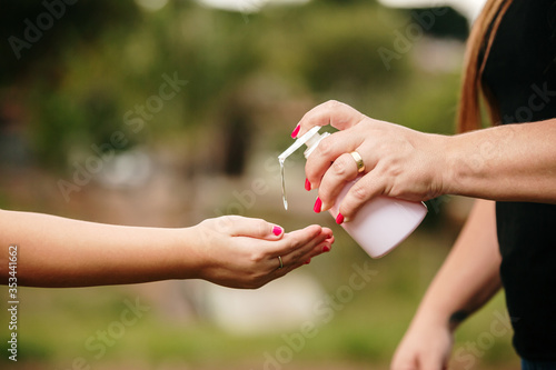 Kid girl is spraying alcohol gel on her hands. Antiseptic cleaning gel in child's hands. Close up. Hygiene during Covid-19 Coronavirus epidemic. © Brastock Images