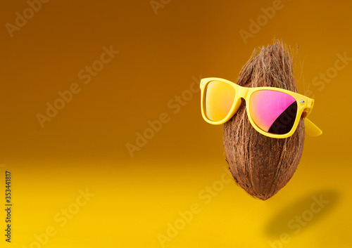 Summer times of funny attractive coconut in stylish sunglasses. minimal fruit concept. Idea creative foods and drinks that are typically enjoyed at summer festivals around the world
