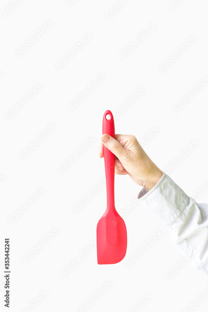 Red silicone spatula in a female hand on a white background Red silicone spatula in a female hand on a white background