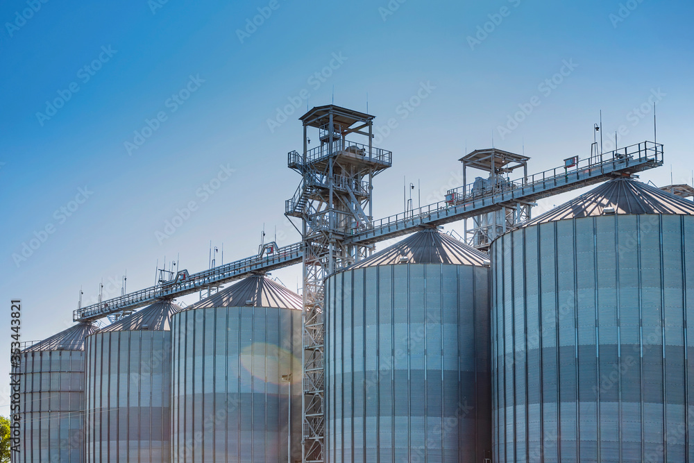 A large modern  agro-processing plant for the storage and processing of grain crops. Fragment of large metal barrels of grain. Granary elevator.
