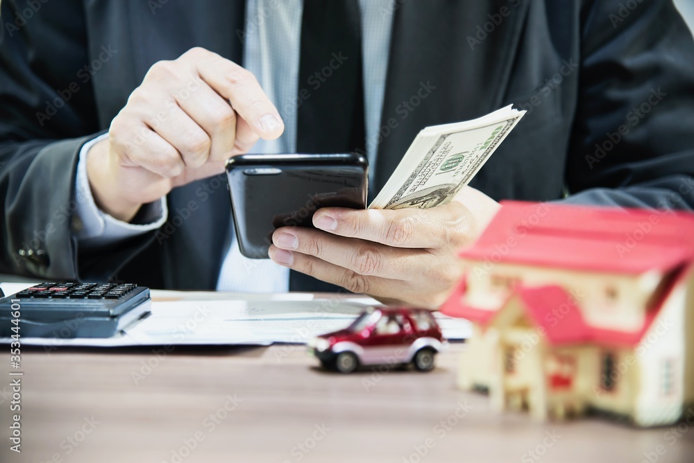 Fototapeta premium Business man counting money dollar note calculating home and car loans - personal financial insurance lifestyle real estate concept