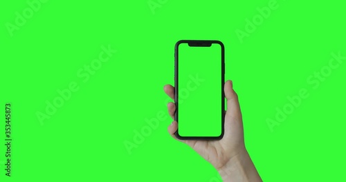 Woman hand holding the smartphone on green screen chroma key background.  Mobile phone mock-up for your product. The iPhone Xr model in vertical orientation portrait mode. USA, California