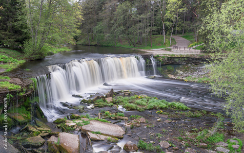 Waterfall in the lower course of the Keila River on North Estonian Klint.  Keila-Joa Castle Schloss Fall (Keila Joa . Smooth surface, broken and fallen rocks and grass, cloudy skyscape. Estonia. photo