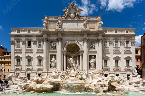 The baroque masterpiece of the Trevi Fountain in Rome, one of the most popular tourist attractions in the city, on a summer afternoon against a blue sky.