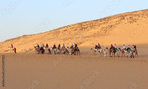 Camel caravan passing through the desert carrying tourists 