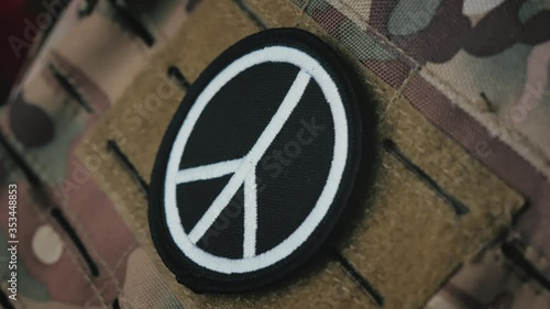 No More War concept: Pacific sign patch on military camouflage equipment. 
Handheld shot.