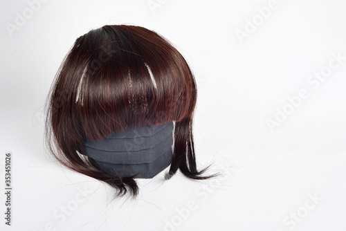 Womens brown wig and a black medical mask on a white background