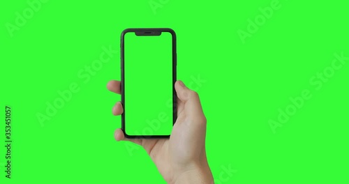 Man hand holding the smartphone on green screen chroma key background.  Mobile phone mock-up for your product. The iPhone Xr model in vertical orientation portrait mode.