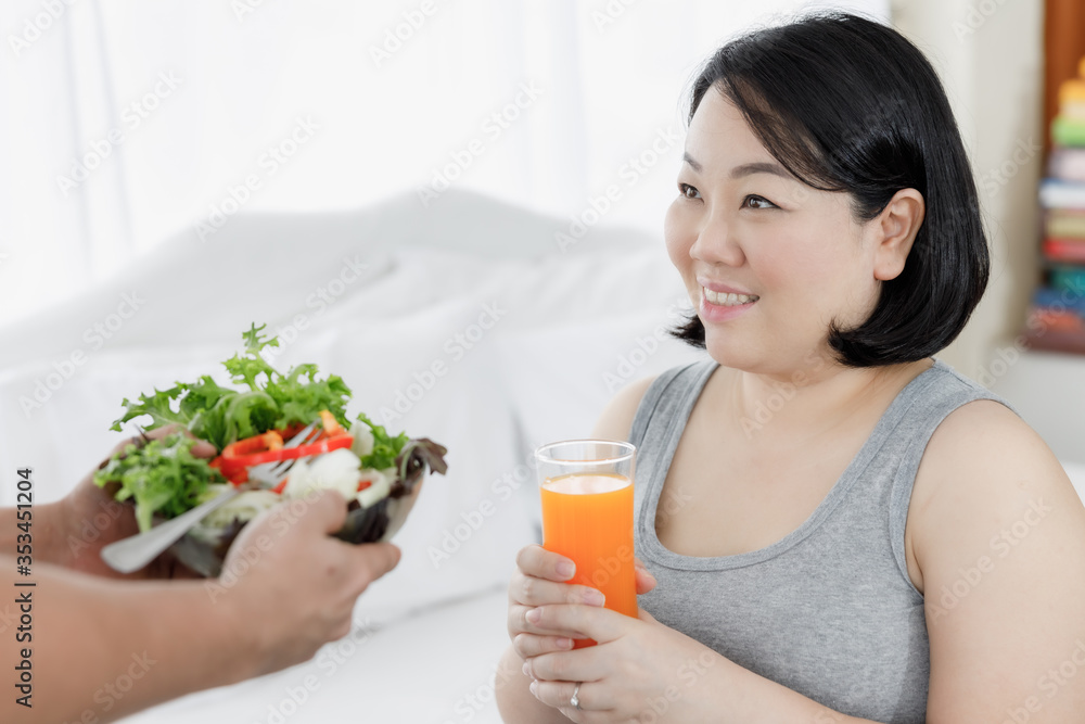 Asian pregnant woman with the juice in hand and salad on hands husband Asian pregnant woman with the juice in hand and salad on hands husband