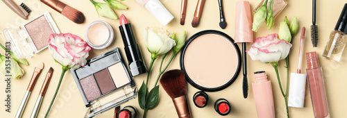 Different makeup cosmetics and flowers on beige background. Female accessories