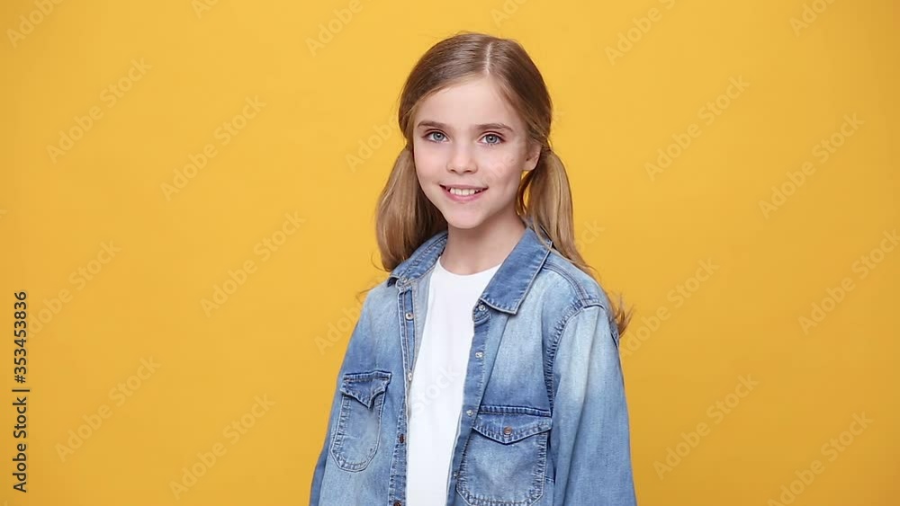 Little blonde kid teen teenager girl 12-13 years old in denim jacket white t-shirt posing isolated on yellow background studio. People childhood lifestyle concept Looking at camera with charming smile Little blonde kid teen teenager girl 12-13 years old in denim jacket white t-shirt posing isolated on yellow background studio. People childhood lifestyle concept Looking at camera with charming smile