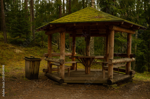 Wooden picnic place in the forest with a trash can