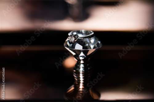 Wedding ring. Soft focus. The wedding ring is decorated with diamonds. On the mirror surface. In the foreground is an artificial diamond.