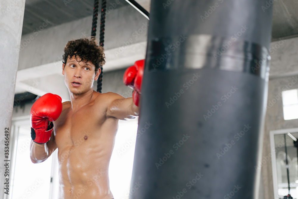 Portrait of young Caucasian muscular strong man in boxing gloves training exercise in gym fitness. Boxer workout punching bag fist. fighting sport