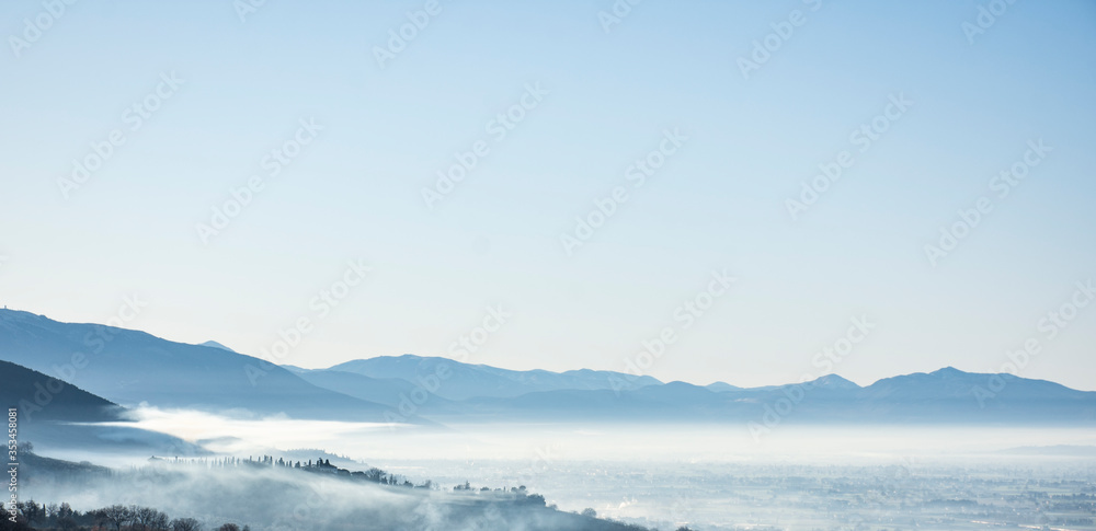 Pueblo ubicado en las colinas durante amanecer de día con niebla