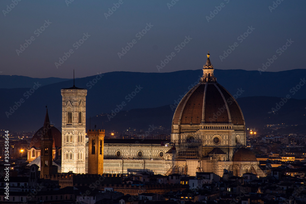 Catedral de Florencia iluminada a la noche con colinas de fondo