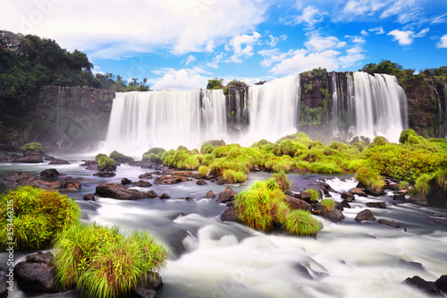 Iguazu waterfalls in Argentina  view from Devil s Mouth. Panoramic view of many majestic powerful water cascades with mist. Long exposure  long water. Panorama of Iguazu valley from high up..